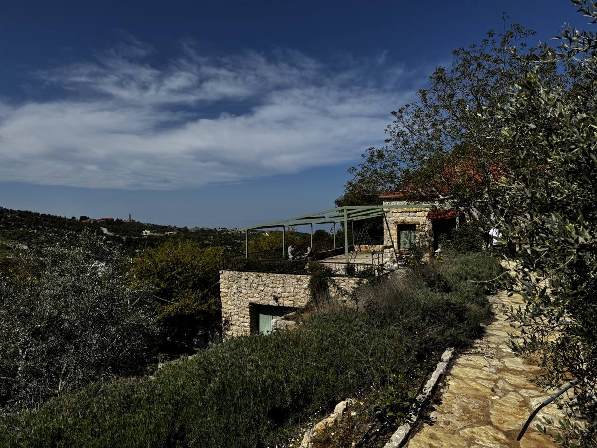 The stone house on its terrace under a wide sky, with the hills behind